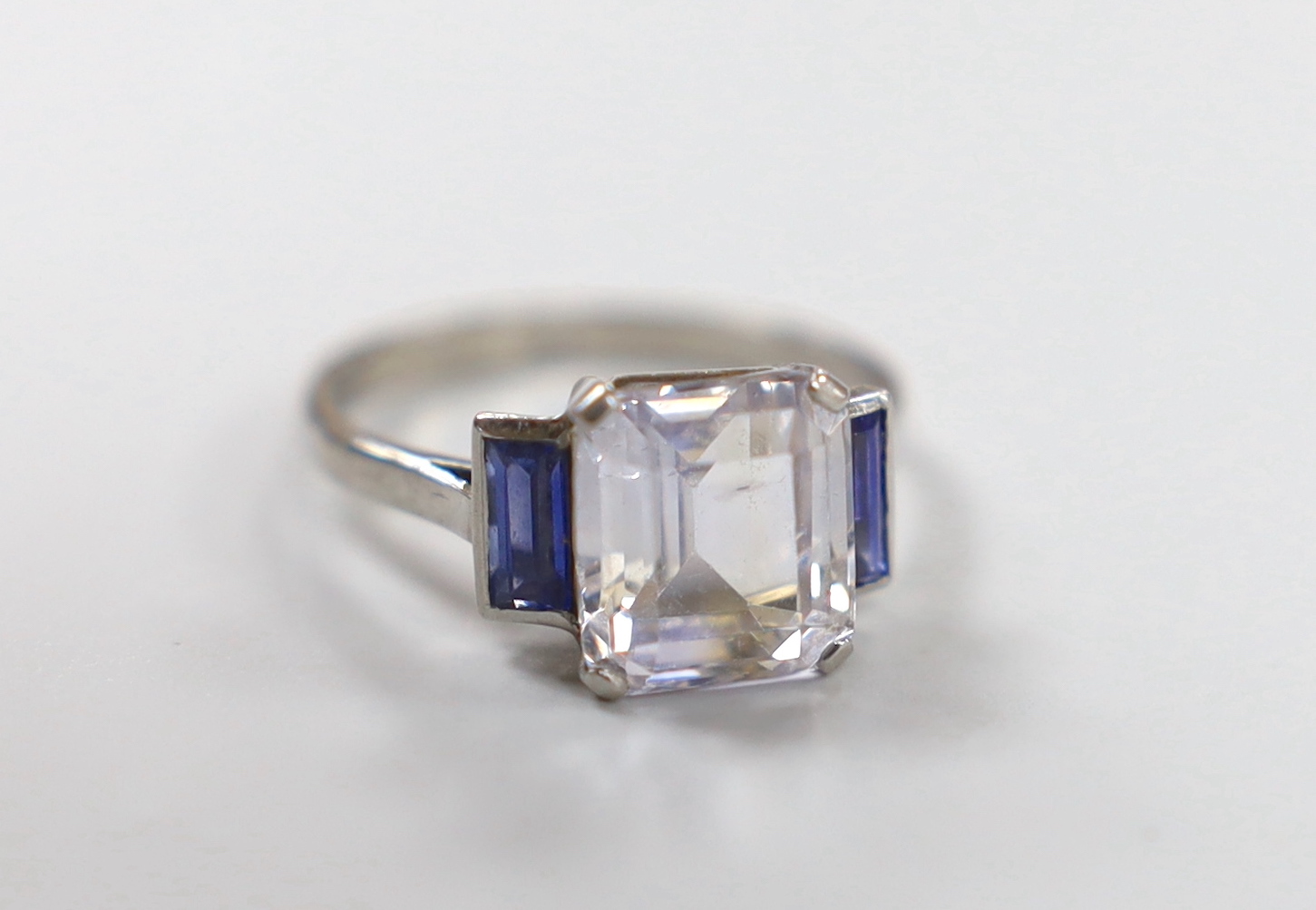 A white metal and two colour sapphire set three stone ring, size N, gross weight 3.8 grams.